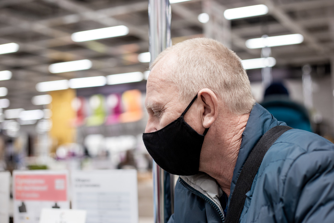 Älterer Mann mit Stoffmaske in einem Geschäft