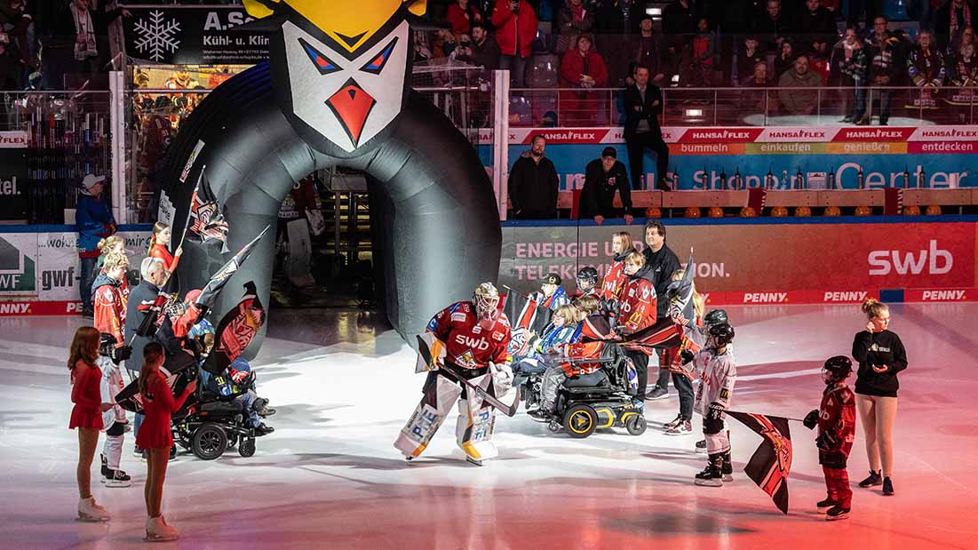 Eishockeyspieler und Menschen mit Behinderung auf der Eisfläche beim Spiel. 